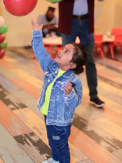A young boy reaching for a balloon, his face full of excitement. It’s these small, joyful moments that I love to see.