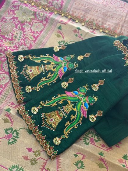 A rich green blouse with sleeves painted in a traditional style, depicting colorful peacocks and temple bells. The artwork is enhanced with kundan and zardosi details.