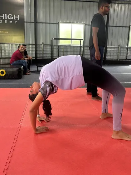 A workshop participant holds a strong bridge pose, demonstrating the flexibility gains from our training.