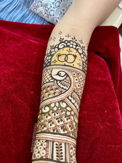 The forearm detail of the engagement mehendi, with the ring symbol surrounded by a beautiful arch.