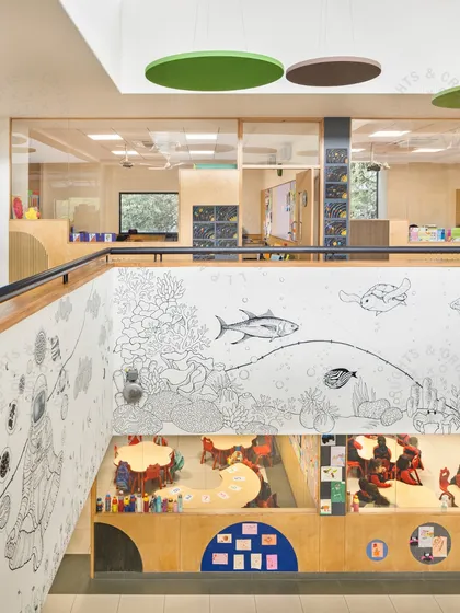 A view from the upper level of the GD Goenka School atrium, looking down on a learning activity. The space is designed with murals and transparent walls to maintain a sense of connection and openness.
