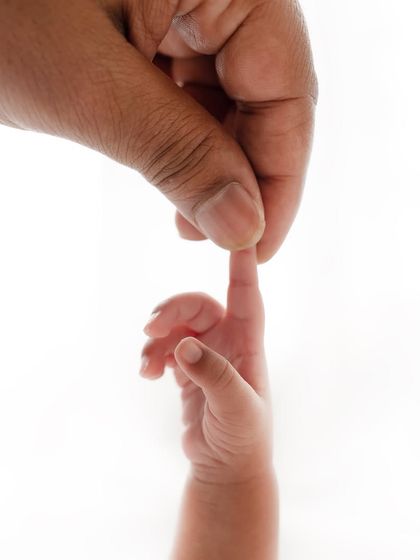 A newborn's tiny finger wrapped around their parent's. This powerful image shows the instant connection and love in a new family.