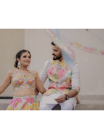 A beautifully composed shot of the couple, the bride's colorful dupatta flowing in the air, capturing the romance of the moment.