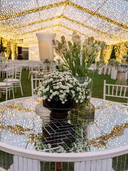 A mirrored tabletop reflects the thousands of fairy lights overhead, creating an endless galaxy of light. This detail from our sangeet decor shows how we use reflective surfaces to amplify the magic and grandeur of the evening.