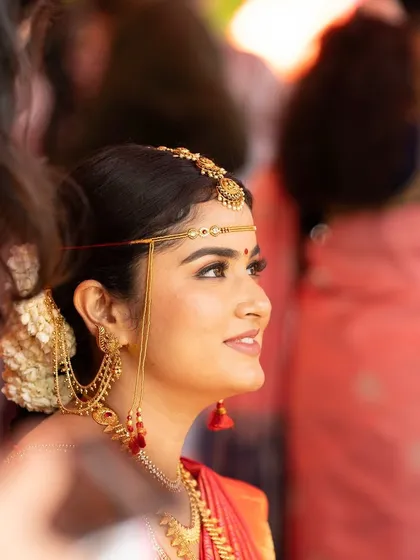 A side profile of the bride during her ceremony. This angle showcases the traditional head jewelry and the clean, defined lines of her eye makeup.