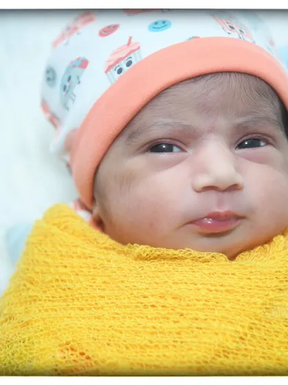 Another angle of this adorable newborn, showing the texture of the yellow knit wrap and their cute printed cap.