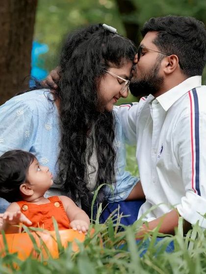A tender kiss for mom while the little one watches on. We capture the love between parents and children in the beautiful, relaxed setting of the outdoors.