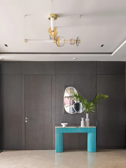 In our modern loft, we used hidden doors with a textured finish to create a sleek and sophisticated look. A bright turquoise console table provides a beautiful contrast against the dark, moody walls.