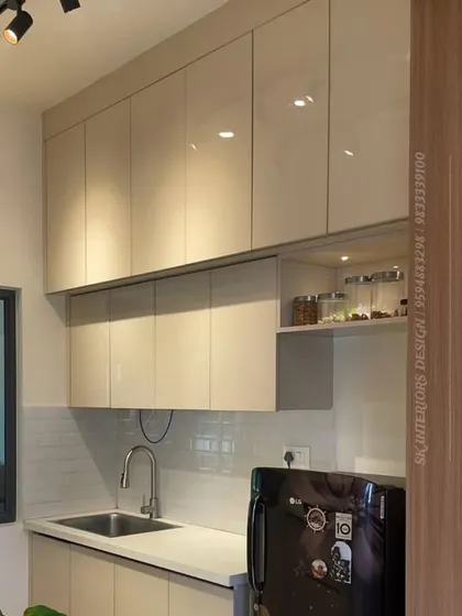A view of a compact kitchen showing the glossy beige overhead cabinets and a dedicated niche for spice jars, ensuring everything is within easy reach.