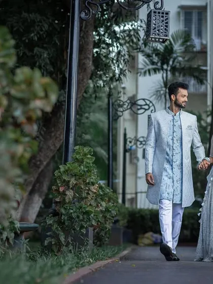 The engaged couple takes a romantic walk together in a park setting.