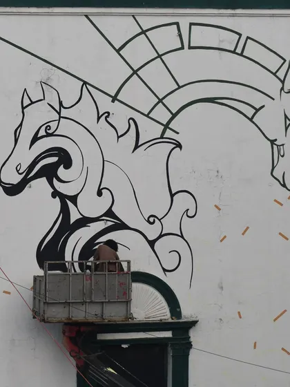 A shot of the horse mural in progress from below. You can see the scale of the artwork against the architecture of the building.