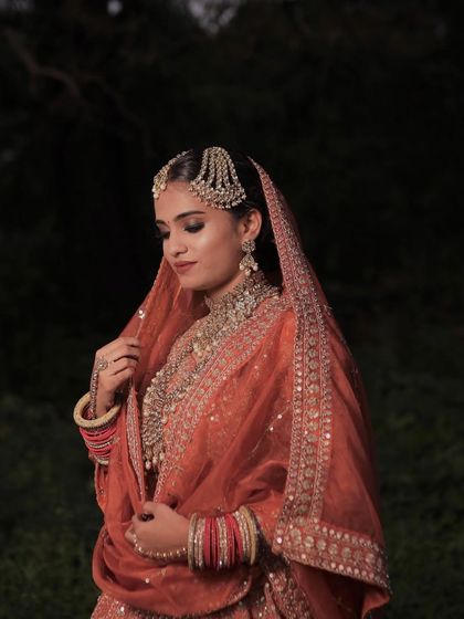An ethereal shot capturing the bride's elegance. The makeup is kept classic with smoky eyes and a neutral lip to balance the vibrant color of her outfit.