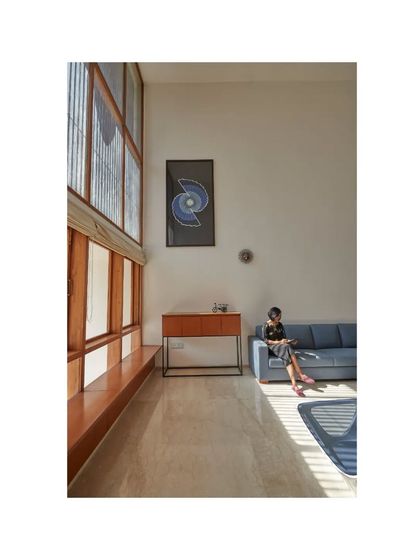 The living room in the Vikas Residence is a study in scale and light. The double-height window wall floods the minimalist space with sunlight, creating a calm and expansive atmosphere.