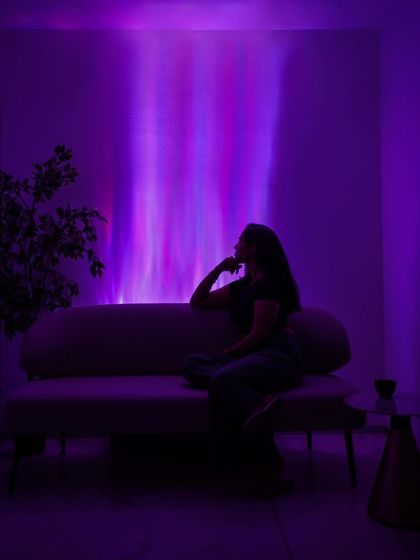 Our lighting is designed to create moods and define spaces. Here, the silhouette of a person relaxing is framed by the gentle, colorful glow of our wall light, illustrating a perfect scene for unwinding.