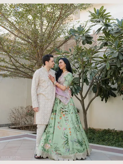 A full-length portrait showcasing a stunning floral lehenga in a palace garden. We work with couples to ensure their outfits and the location create a cohesive and beautiful story.