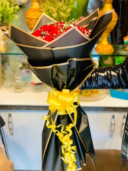 A view of the black-wrapped red rose bouquet being held, showing its scale and how it looks when presented as a gift.