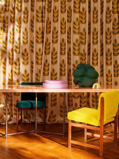 In this dining setting, embroidered drapery from Élitis traces the spirit of a vibrant era. The repeating leaf motif on a matte linen canvas provides a backdrop of subtle texture and timeless expression.