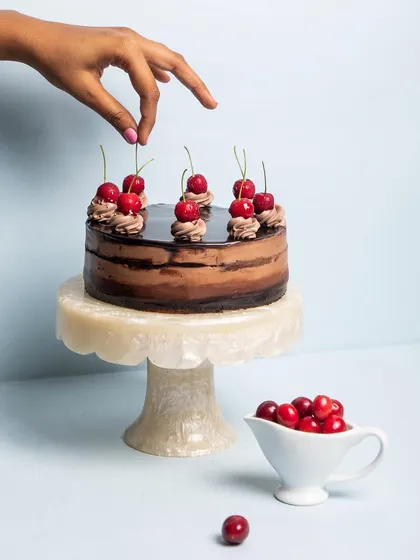 This is my eggless Chocolate Mousse Cake, a dream for any chocolate lover. It has layers of gooey chocolate sponge, light milk and dark chocolate mousse, and a glossy ganache topping, all finished with fresh cherries.