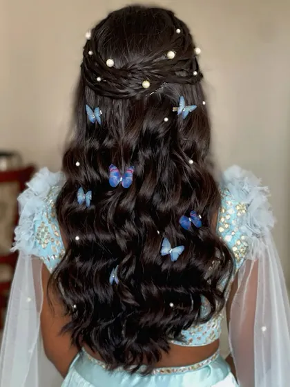 A whimsical hairstyle with a braided crown and cascading curls, filled with blue butterfly clips.