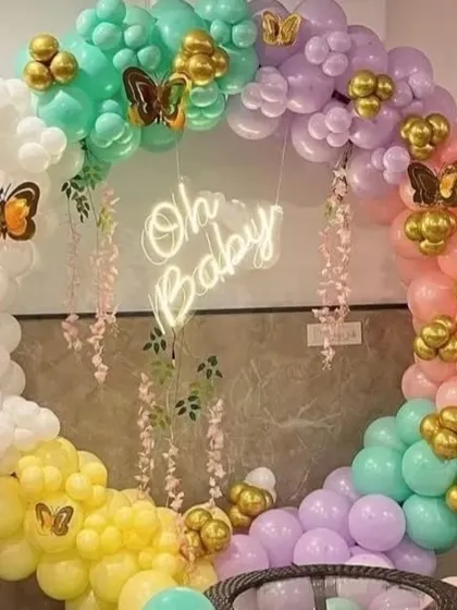 A colorful pastel balloon ring for a baby shower. This "Oh Baby" setup is decorated with gold butterfly accents for a whimsical touch.