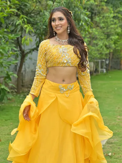 A full-length shot of the model in a garden, her yellow lehenga looking radiant in the natural light.