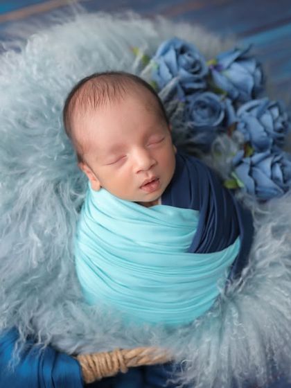 Feeling blue in the best way possible. This newborn is wrapped in shades of blue, surrounded by matching roses. A lovely theme for a baby boy.