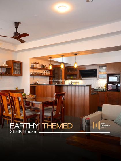 An earthy, natural-themed 3BHK at Total Environment, featuring rich wood tones in the open-plan kitchen and dining area.