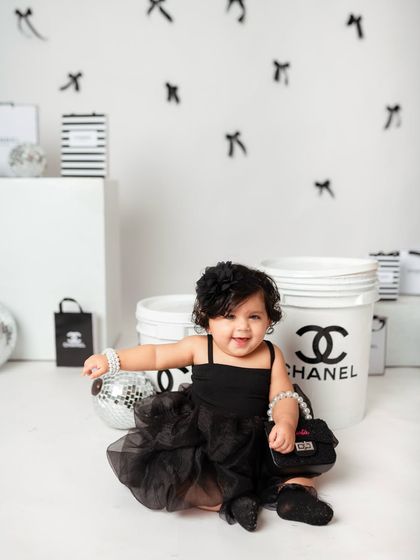 The happiest little fashionista. The younger sister flashes a huge smile, holding her tiny handbag prop.