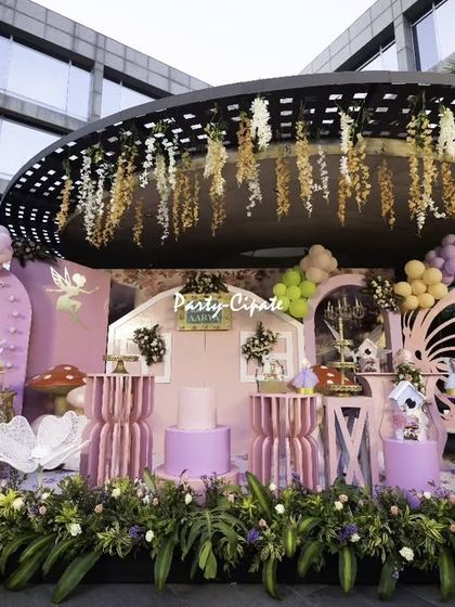 This wide shot shows the full scale of an enchanted fairy party at a hotel. I used the venue's architecture, like this round canopy, and enhanced it with hanging floral arrangements, custom props, and a detailed stage to create a truly immersive experience.