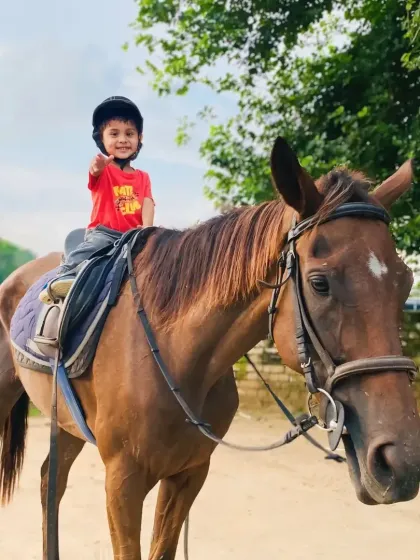 A little rider gives a thumbs-up. We love seeing our kids feel proud and happy during their lessons.