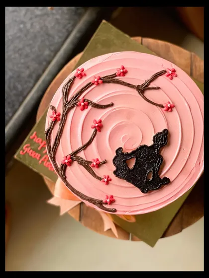 A special cake for Guru Purnima, featuring a silhouette of a person meditating under a cherry blossom tree.