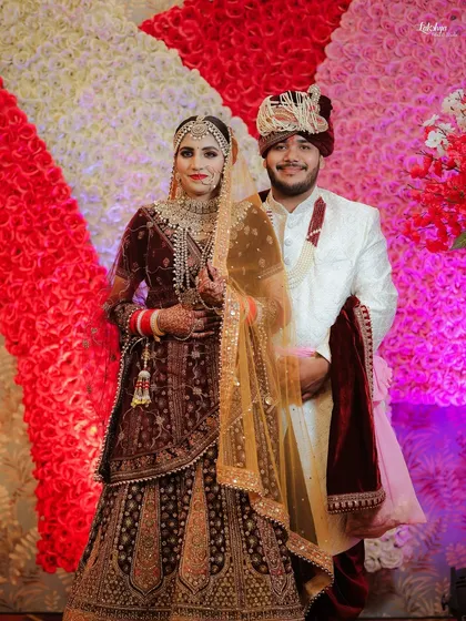 A classic posed portrait of the bride and groom on their wedding day. This shot showcases their beautiful traditional outfits against a vibrant floral backdrop.