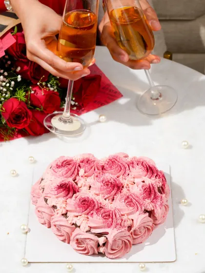 A celebratory "cheers" with two glasses of champagne over the Valentine's cake, capturing a moment of shared joy.