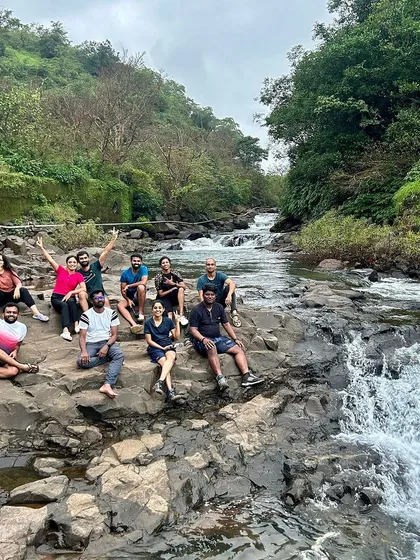 Relaxing on the rocks by a cascading river, enjoying the serene environment.