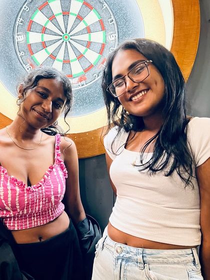 Two friends posing by the dartboard between karaoke sets. There's always something to do while you wait for your turn to sing.