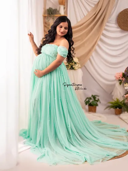 This window-lit shot showcases the delicate details and soft color of the pearl-adorned mint gown.