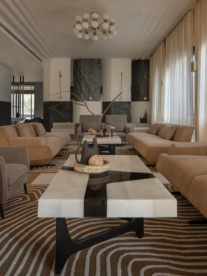 The living space at Urban Oasis plays with scale and contrast. We designed this formal area for a large multi-generational family, using a neutral palette, sculptural furniture, and a striking black and white marble fireplace to create a space that feels both grand and intimate.