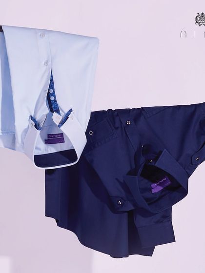 A collection of our premium men's shirts, showcasing different styles from a classic navy to a light blue with a patterned inner cuff.