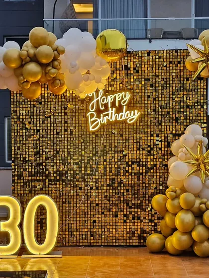 A closer view of the gold sequin wall backdrop, showing the shimmer effect and the arrangement of white and gold balloons.