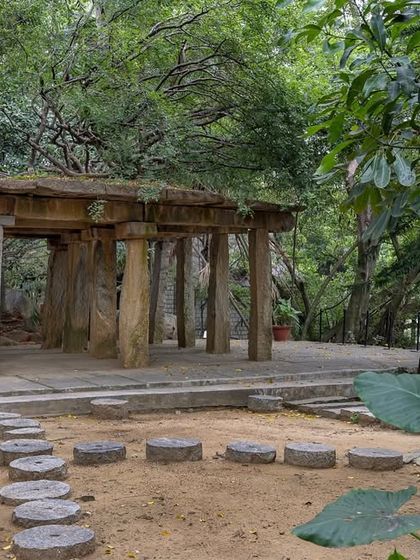 The ancient Stone Mantapa, nestled amidst trees, offers a rustic and historic setting for intimate rituals or beautiful wedding portraits.