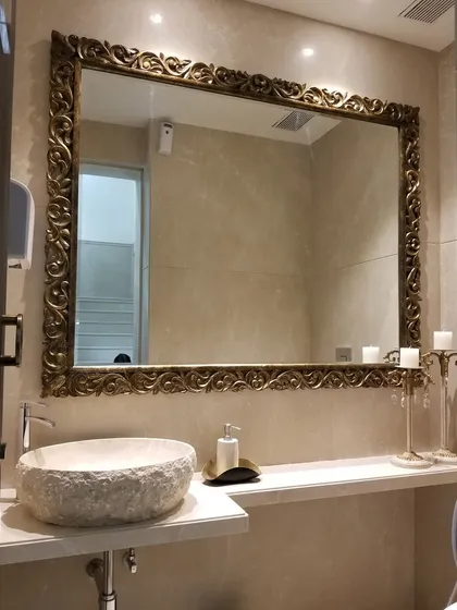 The powder room vanity in the Bellevue lobby. I believe even functional spaces should feel special. Here, an oversized, ornately carved mirror and a rustic stone basin create a dramatic and luxurious atmosphere for guests.