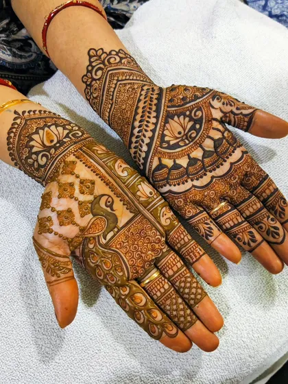 This anniversary mehndi combines two different styles. One hand features a beautiful peacock and checkered patterns, while the other has a more traditional layout with lotus and dome motifs.