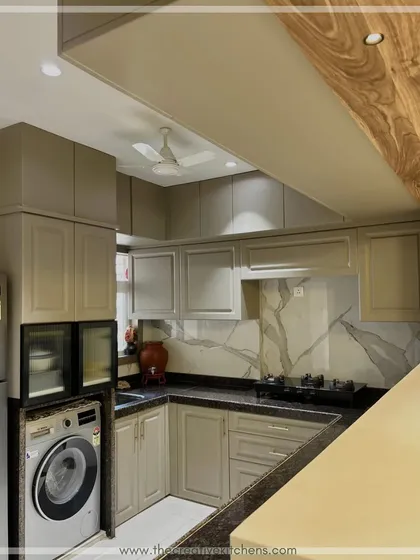 An overhead view highlights the L-shaped layout and the effective use of space. The design incorporates a utility area with a washing machine, proving that practical needs can be met without sacrificing style.