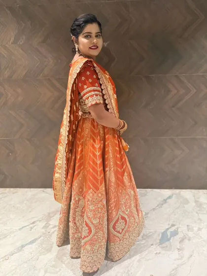 A side view of the client in the orange lehenga, showing the drape of the dupatta.