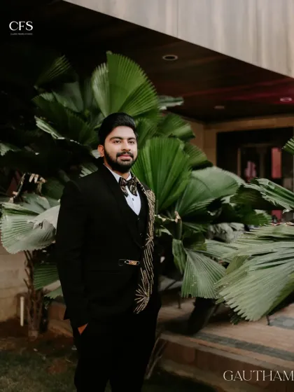 A portrait of the groom looking sharp and confident in his reception suit. The lush green background provides a great contrast to his dark, stylish attire.