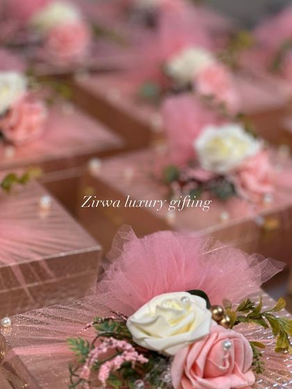 A close-up of some of the beautiful pink-themed wedding favor boxes I have created. The textured pink boxes are topped with delicate flowers and tulle.