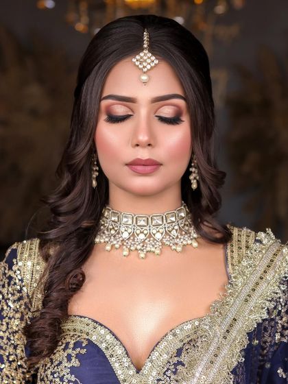 A beautiful engagement or reception look in a royal blue and gold lehenga. The makeup features a classic brown smokey eye and a flawless matte base.