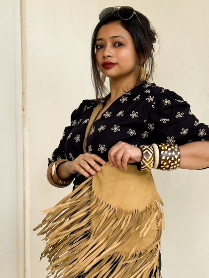 I'm all set for a Friyay party in this all-black boho look. A black embroidered romper paired with a suede fringe bag and chunky wooden bangles creates a Y2K-inspired, party-ready outfit.