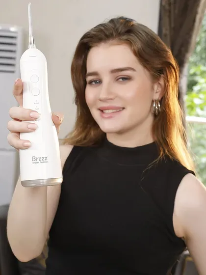 A model presents a white water flosser, showcasing its clean design. This type of shot, featuring a model interacting with the product, is highly effective for e-commerce and social media.