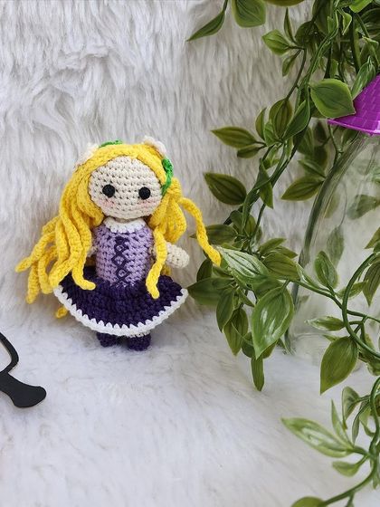 Disney Princess Rapunzel, with her long, flowing yellow hair decorated with flowers. Her purple dress is detailed with corset lacing, just like in the movie Tangled.